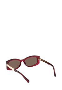 Kissamiskulmaiset aurinkolasit, joissa on tummanruskeat linssit, burgundinpunaiset läpinäkyvät kehykset ja kultaiset yksityiskohdat saroissa. Kiiltävä pinta, tyylikäs muotoilu.