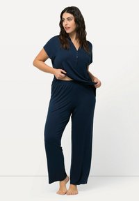 Mörkblå loungewear-set inkluderar en kortärmad topp med knapplist och vida byxor med elastisk midja. Mjuk, flödande tyg.