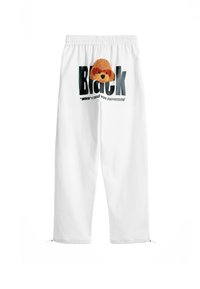 Pantalones de chándal blancos con una cintura elástica. Presenta un parche de perro marrón texturizado y un texto negro en negrita que dice "Black" con un texto más pequeño debajo.