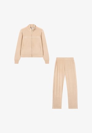 Beige velvet trainingspak met een ritsjack met hoge kraag en zijzakken, gecombineerd met tapered broek en witte accentstrepen.
