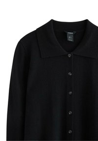 Sort strikket cardigan med rund krave, syv knaplukninger og en blød tekstur. Lavet af let materiale, delvis ærmedesign.