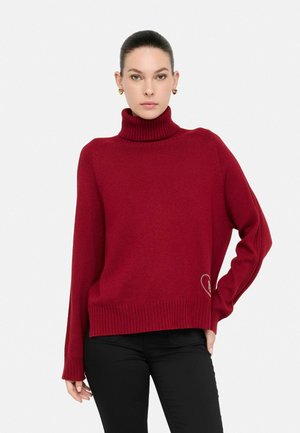 Maglione rosso a collo alto in tessuto lavorato a maglia, con polsini e orlo a coste, dotato di un piccolo dettaglio di cuore ricamato di lato.