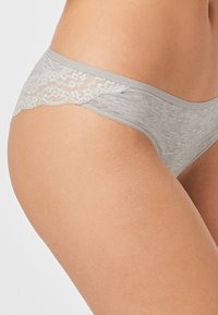 Grijze katoenen string met kantafwerking aan de achterkant, zachte textuur, low-rise ontwerp, met een delicaat bloemenpatroon op het kant.