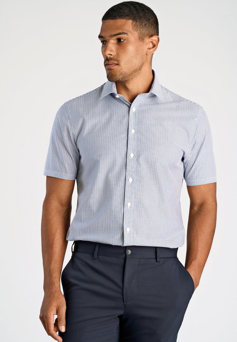 Camicia a maniche corte con bottoni di colore azzurro chiaro, decorata con righe verticali bianche. Presenta un colletto classico e una texture di cotone liscia.
