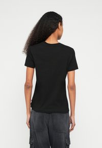 Čierne bavlnené tričko s krátkym rukávom a okrúhlym výstrihom, s jednoduchým dizajnom a miernou elasticitou pre pohodlie.