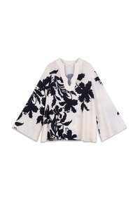 Haut à imprimé floral crème avec motifs noirs, doté d'un col en V profond et de larges manches évasées. Texture douce avec une coupe ample.