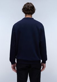 Sweat-shirt bleu marine avec col rond côtelé, manches longues et coupe décontractée. Tissu lisse avec une texture uni et sans marquage visible.