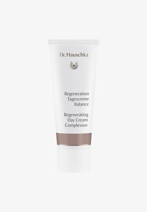 Crème de jour régénérante Dr. Hauschka dans un tube en plastique blanc avec des accents marron, affichant du texte noir et un logo circulaire.