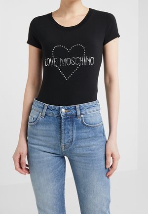 Haut noir ajusté à manches courtes avec contour de cœur en strass et texte "LOVE MOSCHINO" associé à un jean bleu taille haute.