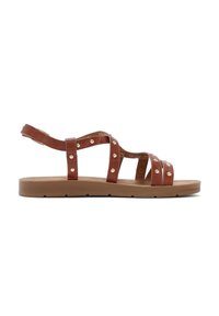 Brown strappy sandal with decorative gold studs, flat rubber sole, adjustable ankle strap, and a smooth texture.