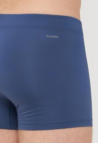 Temno modri kopalni šortsi iz gladkega, elastičnega materiala, ki nosijo logo CLIMACOOL. Oblika vključuje tesno prileganje in minimalistične šive.