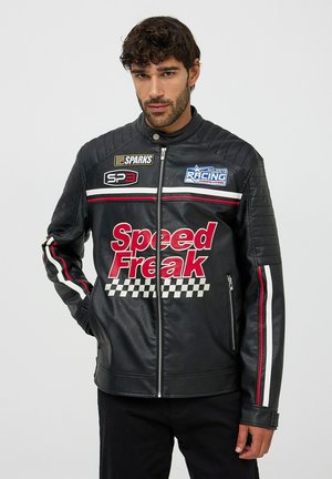 Giacca da corsa in pelle nera con spalle imbottite, strisce rosse e bianche, e grafica "Speed Freak" con accenti a motivo a scacchi.