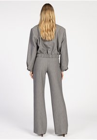 Grijs twee-delig outfit met een cropped top met elastische taille en lange mouwen, en broek met wijde pijpen. Gelaagde stof met een subtiel patroon.
