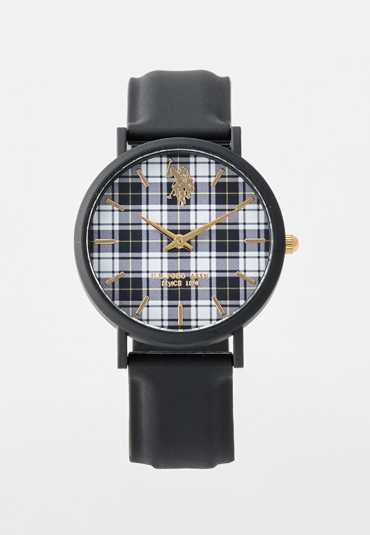 Montre avec un bracelet en caoutchouc noir et un cadran rond, ornée d'un motif plaid blanc et noir, d'accents dorés et d'index des heures dorés.