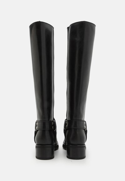 Botas de cuero negras hasta la rodilla con un acabado suave, puntera redondeada y una correa con detalles de metal alrededor del tobillo.