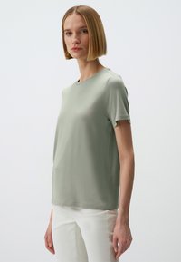 T-shirt a maniche corte, con collo a girocollo, in morbido tessuto verde chiaro. Design semplice con vestibilità rilassata e dettagli delle cuciture minimi.
