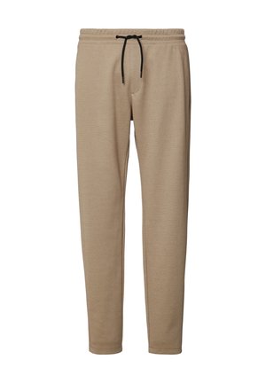 Beige Jogginghose mit Kordelzug und schmal zulaufenden Beinen in weicher Textur. Mit einer Vordertasche und genähten Nähten.