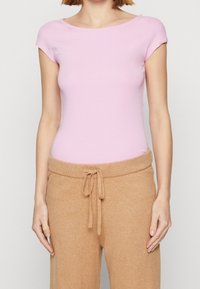 Light pink short-sleeve bodysuit paired with soft, beige high-waisted trousers featuring a drawstring waist. Smooth texture, form-fitting design.