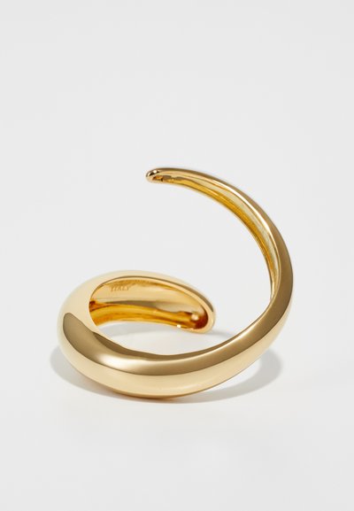 Gold-colored metal cuff bracelet with a smooth, curved design. Features a shiny, reflective surface and seamless ends, creating an elegant silhouette.