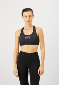 Sujetador deportivo negro con logo de Nike rosa, hecho de material suave. Combinado con leggings negros de cintura alta, que cuentan con un diseño sin costuras.