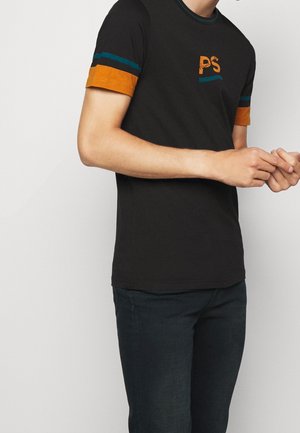 T-shirt noir à manches courtes avec des rayures orange et bleu sarcelle sur les manches et un logo "PS" sur la poitrine. Tissu en coton lisse.