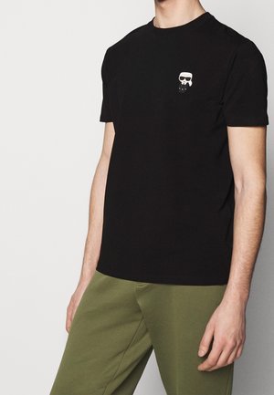 Schwarzes T-Shirt mit rundem Ausschnitt, kurzen Ärmeln und einer weißen Cartoon-Figur-Grafik auf der linken Brust. Weiches Baumwollmaterial.