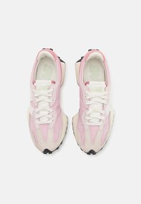 Zapatillas rosas y beige con parte superior de malla, acentos de ante, cordones blancos y suela de goma negra. Presenta un logo en la lengua.