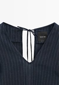 Tmavé šaty s proužky, výstřihem do V a detailem zavazování na zádech, s visačkou Massimo Dutti uvnitř výstřihu.