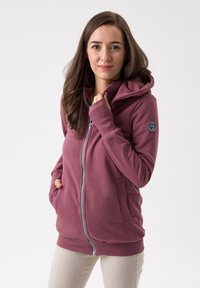 Felpa con cappuccio e zip in rosa polveroso, dotata di tasche, polsini e orlo a coste, e una patch rotonda con il logo sulla manica sinistra.