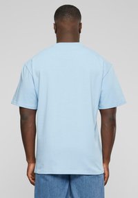 T-shirt bleu clair à manches courtes et col rond, fabriqué en tissu doux, présente une coupe décontractée et un design de dos sans coutures.