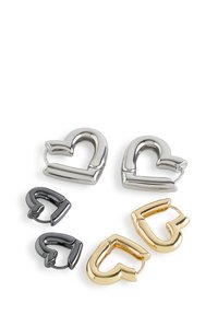 Fermoirs en forme de cœur en argent, or et métal noir. Deux grands cœurs argentés et un en or, avec des surfaces lisses et brillantes et des lignes épurées.