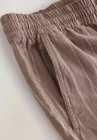 Bruine linnen broek met een elastische tailleband, voorzien van witte verticale strepen en zijzakken. Gelaagd materiaal met een relaxte pasvorm.