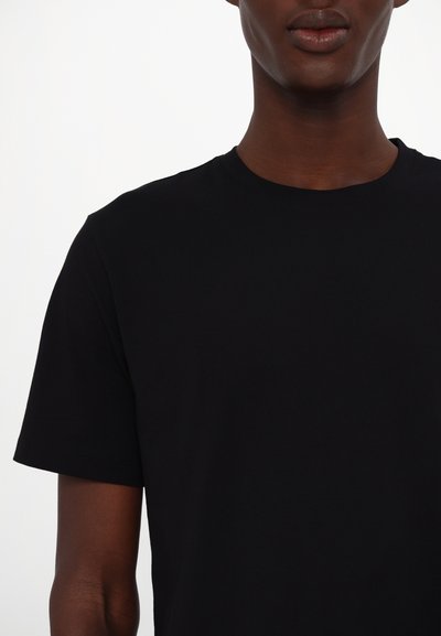 T-shirt en coton noir avec un col rond, des manches courtes et une texture lisse. Design minimaliste sans motifs ni logos visibles.