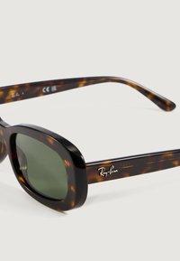 Gafas de sol Ray-Ban de carey con lentes rectangulares verde oscuro y logo en la patilla, exhibidas sobre una superficie blanca.
