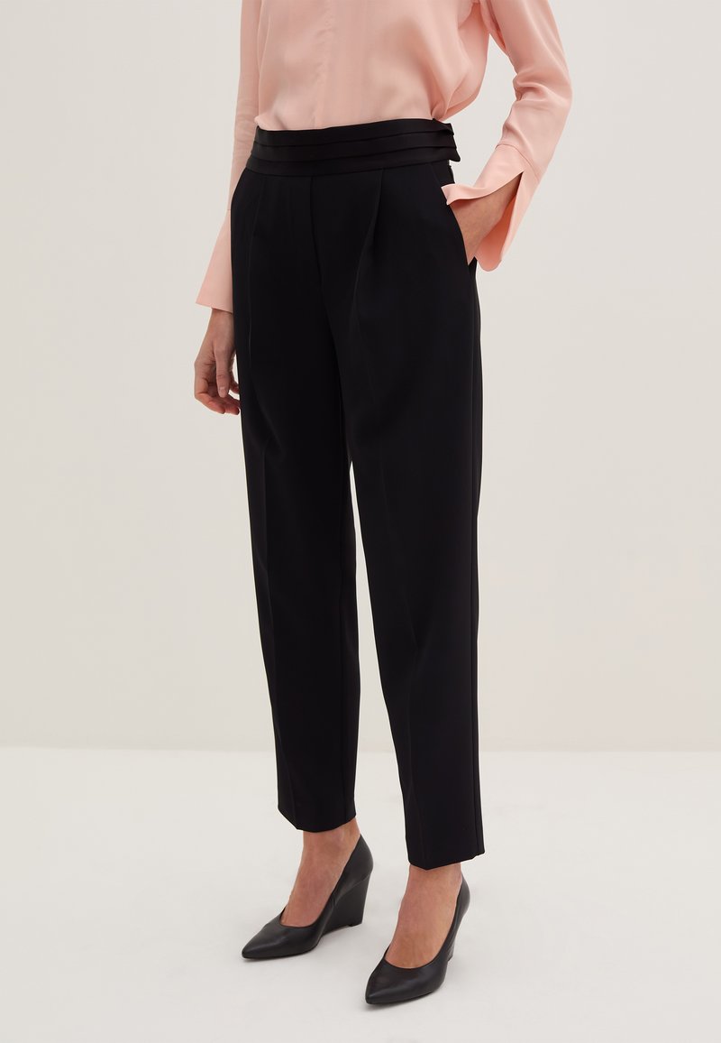 Schwarze Maßhose mit hoher Taille und Bundfalten, kombiniert mit einer hellrosa Bluse. Strukturierter Stoff mit einer eleganten Silhouette.