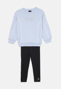 Ανοιχτού μπλε φούτερ με λευκές λεπτομέρειες και κέντημα "Jordan", συνδυασμένο με μαύρες κολάν που διαθέτουν το λευκό λογότυπο Jordan. Υλικό από ίνες βαμβακιού.