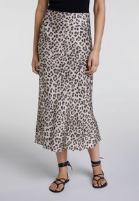 Falda midi de estampado de leopardo en tejido suave, con base color beige claro y manchas marrón oscuro, que presenta un dobladillo acampanado y se combina con sandalias negras de tiras.