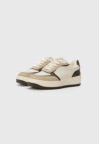 Sneakers w kolorze beżowym, kremowym i ciemnobrązowym. Wykonane ze skóry i zamszu, z perforowanymi detalami i płaskimi sznurówkami.
