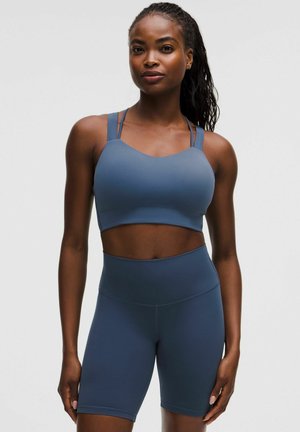Blue athletic crop top with thin straps and matching high-waisted shorts, made of stretchy fabric, featuring a smooth texture and minimal seams.