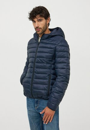 Giacca a vento blu navy con cappuccio e chiusura a zip, caratterizzata da un design trapuntato, due tasche laterali e polsini a coste per maggiore calore.