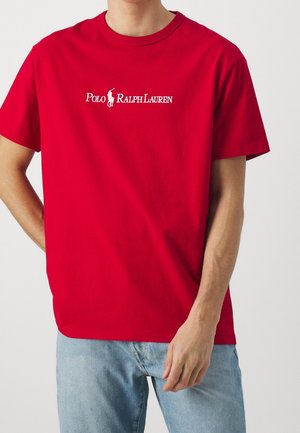 Czerwona bawełniana koszulka z okrągłym dekoltem, na której białą haftowaną literą znajduje się logo "Polo Ralph Lauren" na wysokości klatki piersiowej. Standardowy krój, krótki rękaw.