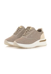 Baskets beige clair avec une tige en tissu texturé, un design à lacets, un col rembourré et une semelle blanche avec une bande dorée.
