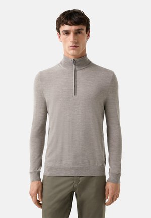 Un sweat zippé gris clair en tissu doux, avec un col montant et des manches longues dotées d'une texture subtile.