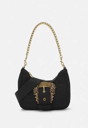 Czarna torebka Versace Jeans Couture ze złotą ozdobną klamrą i grubym złotym łańcuszkowym uchwytem, wyposażona w szeroki materiałowy pasek na ramię.