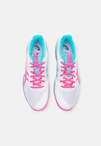 Chaussures de sport avec une tige en maille blanche, des lacets roses et des accents turquoise. Elles disposent d'un col rembourré et d'une semelle texturée pour une meilleure adhérence.