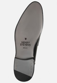 Semelle de chaussure en cuir noir avec une forme arrondie, semelle intermédiaire grise et clous en métal. "HENRY STEVENS BERLIN" est embouti sur la surface.