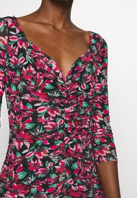 Robe fleurie avec un fond noir orné de motifs floraux roses et verts vifs, manches courtes et fronces au niveau de la poitrine.