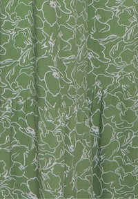 Tissu vert avec des contours floraux abstraits blancs et des détails de coutures froncées créant des plis texturés.
