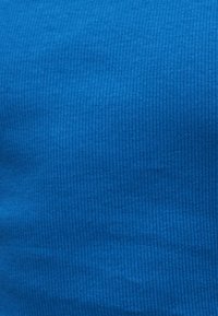 Μπλε ύφασμα με ραβδώσεις, κάθετες υφασματικές γραμμές και ελαφριές ρυτίδες.