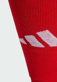 Red sports sock with ribbed texture featuring a white zigzag pattern across the upper section. Designed for athletic use.